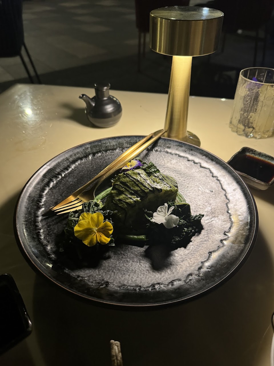 Green plated dish with edible flowers under warm table light